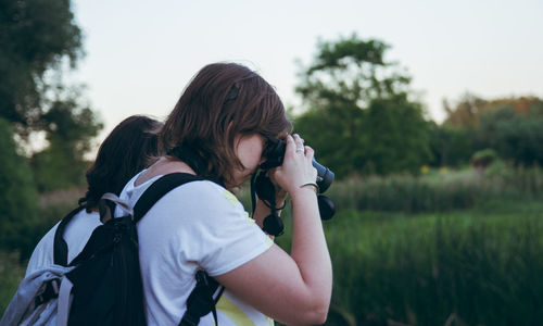 Woman photographing with camera on field