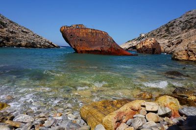 Scenic view of rocks in sea against clear sky