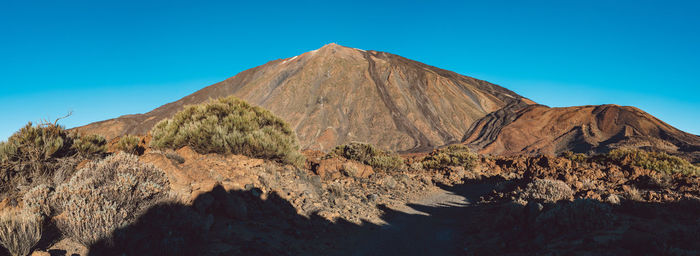 Panoramic view of arid landscape against clear blue sky