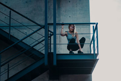 Low angle view of woman crouching on staircase