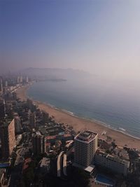 High angle view of cityscape by sea against clear sky