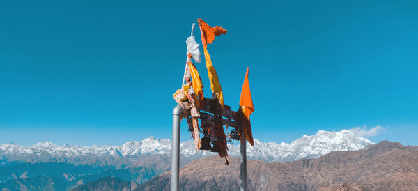 Traditional windmill on snowcapped mountain against blue sky