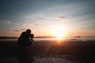 Silhouette people on beach against sky during sunset