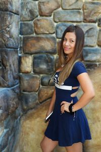 Portrait of young woman standing against brick wall