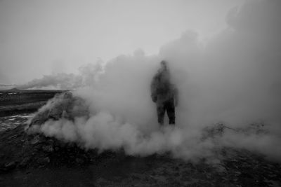 Person standing amidst smoke at volcanic landscape