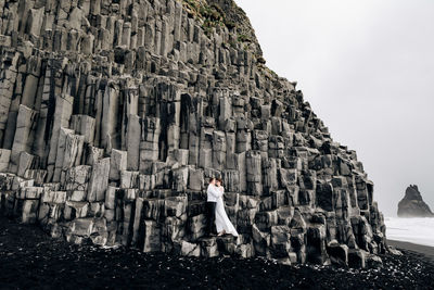 Woman standing on rock against sky