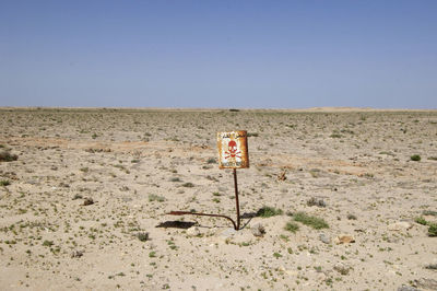 Road sign in desert against clear sky