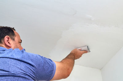 Man holding sandpaper while polishing a ceiling