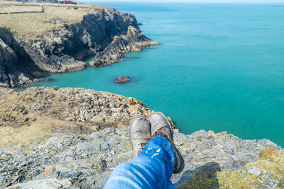 Low section of person on rock against sea