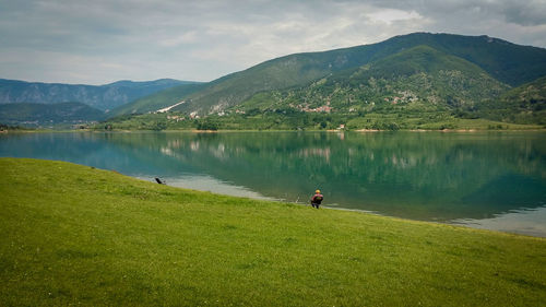 Scenic view of lake by mountains against sky