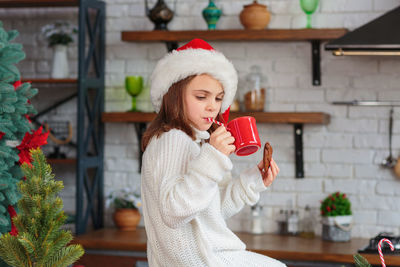 Portrait of young woman drinking juice in kitchen