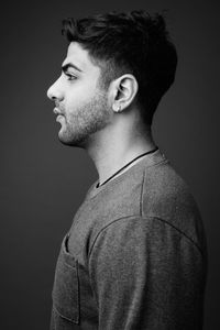 Portrait of young man looking away against black background