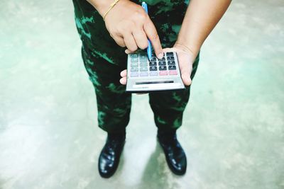 Low section of army soldier using calculator