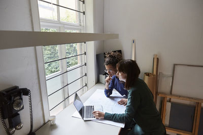 Woman using mobile phone while sitting on table