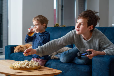 Boy eating food sitting on table