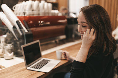 Adult confident business woman freelancer working in a coffee shop cafe using a laptop and phone