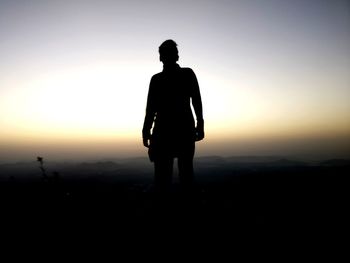 Silhouette man standing on shore against sky during sunset