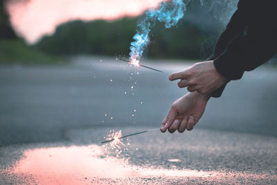 Cropped hands holding sparklers