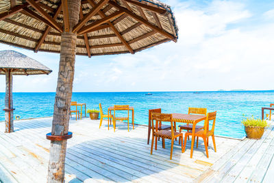 Chairs on table by sea against sky