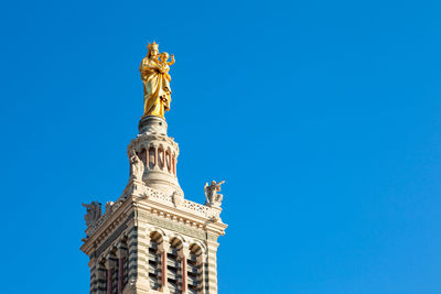 Low angle view of statue against blue sky