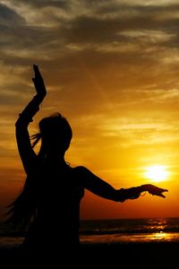 Silhouette woman standing by sea against sky during sunset