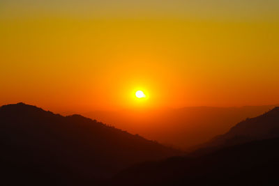 Scenic view of silhouette mountains against romantic sky at sunset