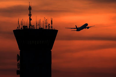 Silhouette airplane flying against sky during sunset