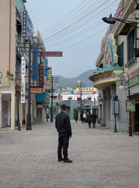 Rear view of woman walking on street amidst buildings in city