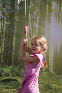 Side view of girl standing against trees in forest