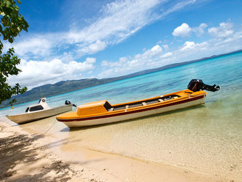 Boat moored on beach against sky