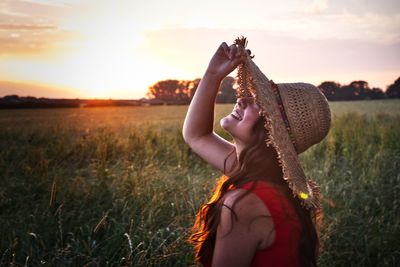 Midsection of woman standing on field against sky during sunset