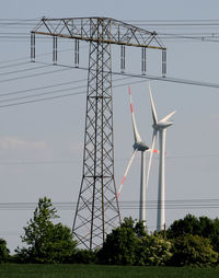 Low angle view of wind turbines against sky