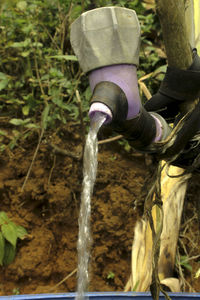 Close-up of human hand against waterfall