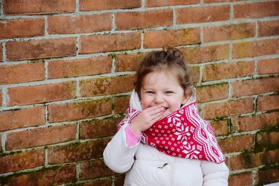 Cute smiling girl against brick wall