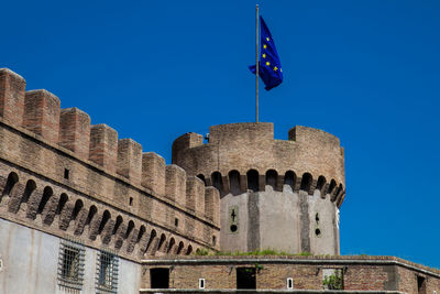 Low angle view of flag on building against blue sky