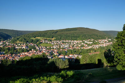 Scenic view of field by buildings against clear blue sky