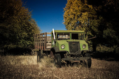 Abandoned truck on field against clear blue sky