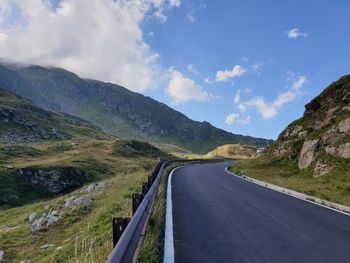 Empty road amidst mountains against sky