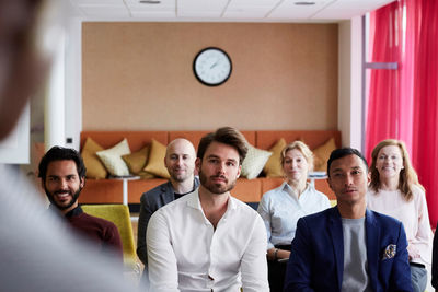 Male and female colleagues looking at entrepreneur giving presentation in office seminar