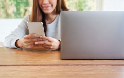 Midsection of woman using laptop at table