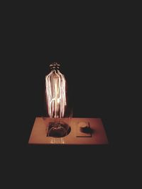 High angle view of illuminated lamp on table against black background