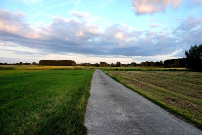 Road amidst field against sky