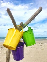 The bucket hung on a dry branch behind the beach and the sea. the sky was dark blue with clouds.