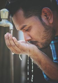 Close-up of man drinking water from tap