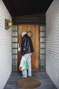 Rear view of man carrying bag opening door