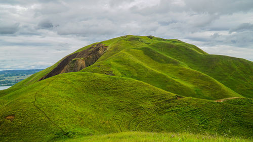 Scenic view of green landscape against dramatic sky