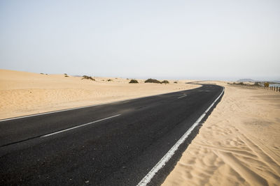 Road amidst desert against clear sky