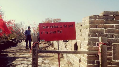 Rear view of man standing by road sign against clear sky