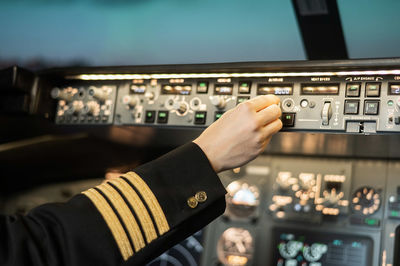 Cropped hand of pilot accessing knob in plane