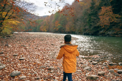 Rear view of person standing on rock during autumn